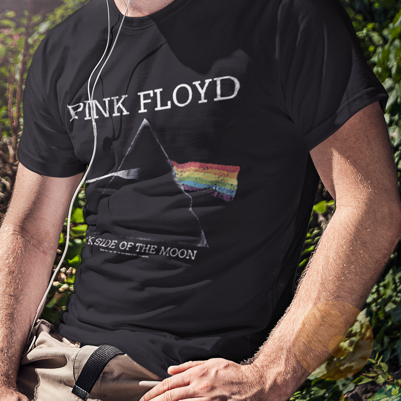 Man with headphones is sitting wearing a Pink Floyd t-shirt. 