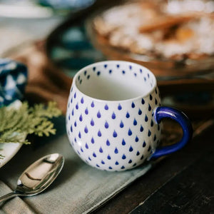 Breakfast table arrangement with ceramic mug in raindrop pattern.