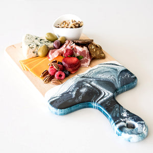 Acacia Resin Cheeseboard in navy and white, with fruits and cheese on it.