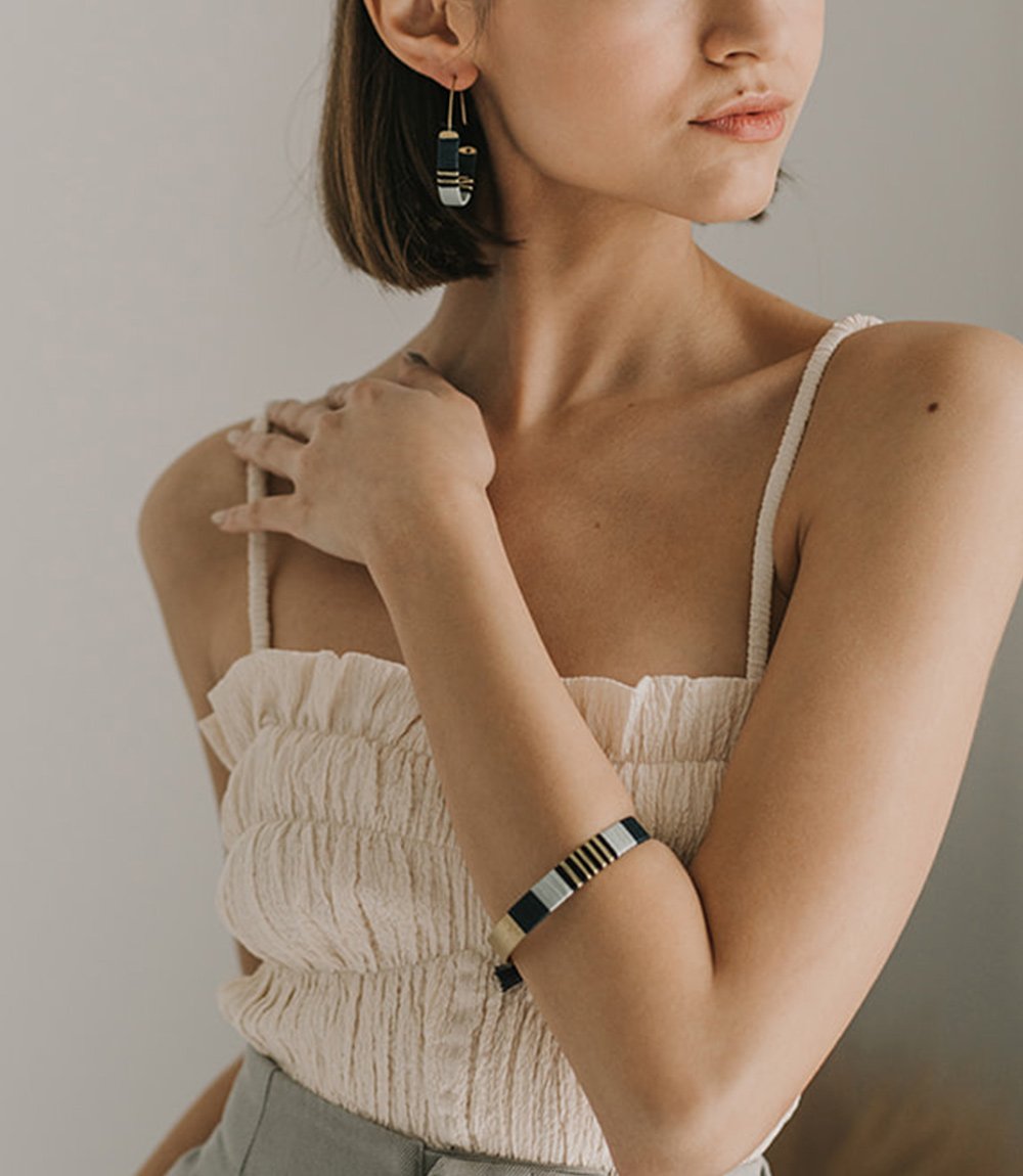 Stripe cuff bracelet on model, wearing matching earrings.