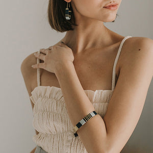 Stripe cuff bracelet on model, wearing matching earrings.