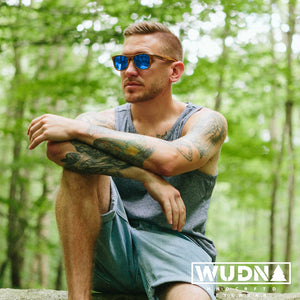 Man sitting outdoors wearing all wood sunglasses with blue mirrored lenses. 