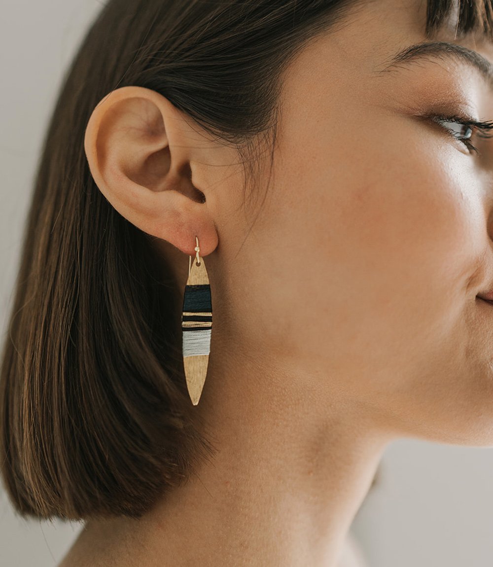 Striped gold drop earrings on model.