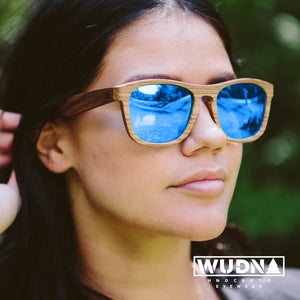 Close up of woman wearing all wood sunglasses with blue mirrored lenses. 